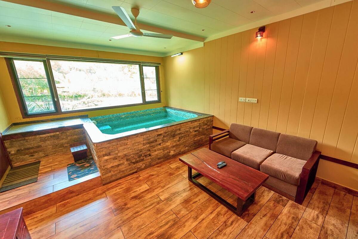 Une pièce avec un plancher en bois, un canapé, une table, une fenêtre et un jacuzzi intégré.
