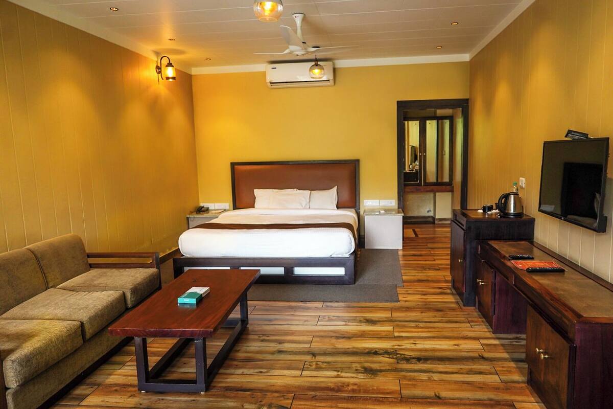 Une chambre d’hôtel comprenant un lit, un canapé, une table basse, une télévision et une kitchenette.