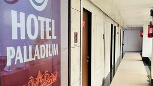 A hotel corridor with doors, a clock, and a welcome sign. - Hotel Palladium (Surat)