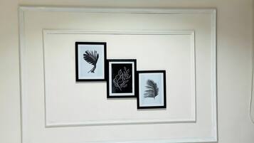 Três molduras com desenhos de folhas em uma parede branca.