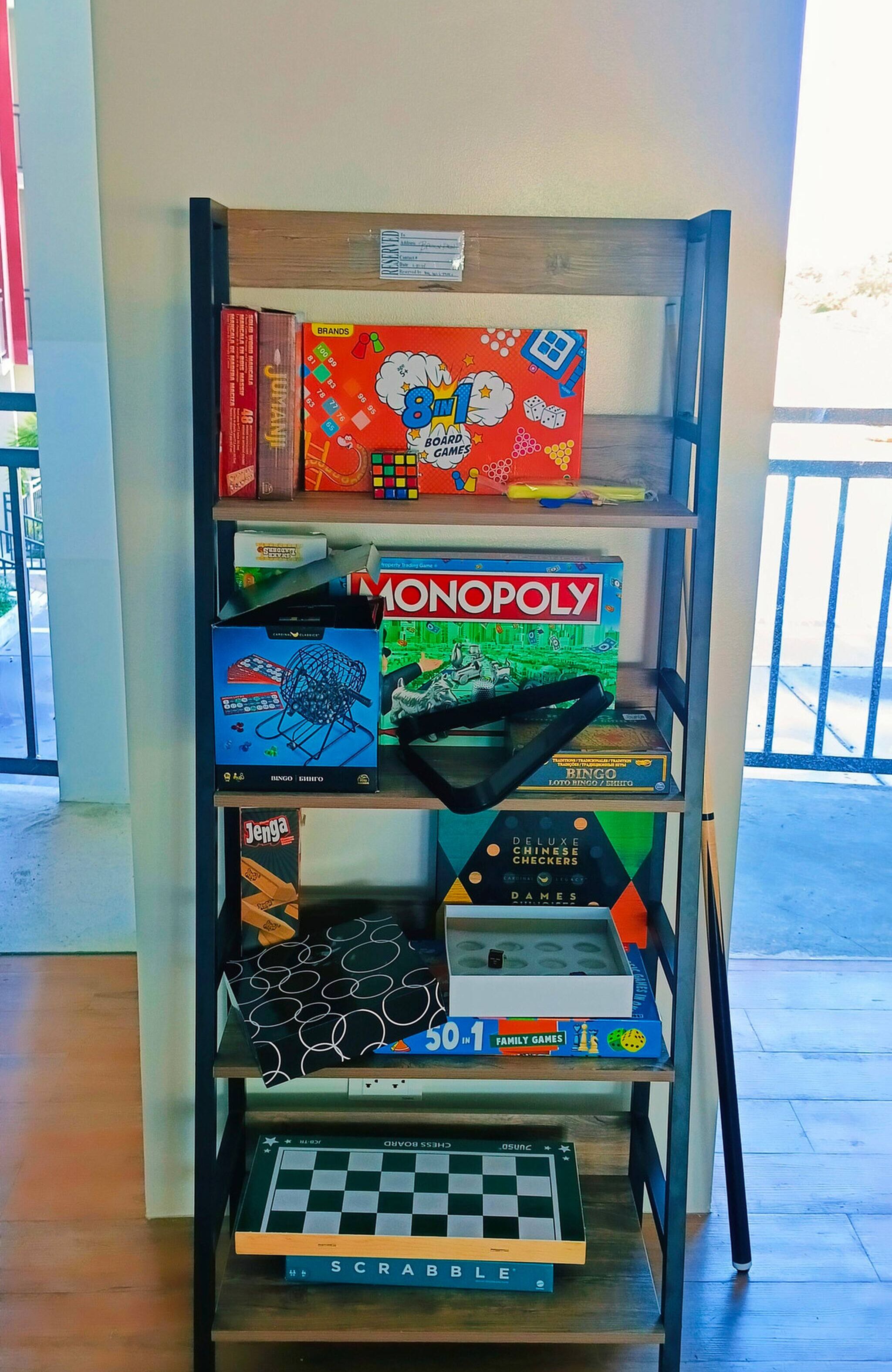 A shelf with various board games including Monopoly, Scrabble, and 8t.