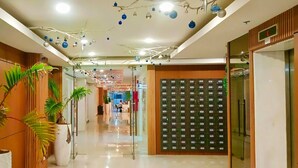 Corredor de hotel com um diretório, plantas em vasos e design moderno no teto.