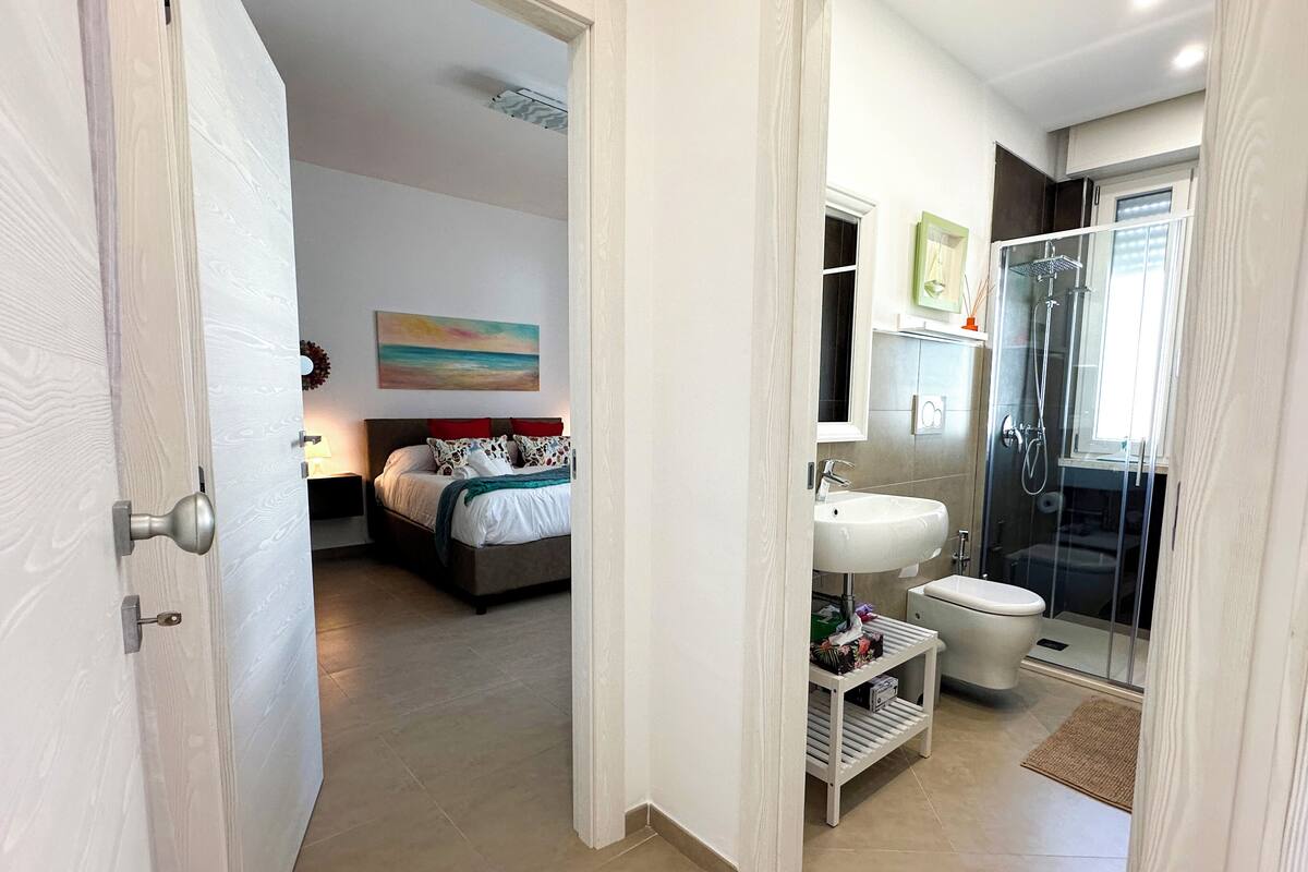 A modern bedroom with a bed, bedside table, and a painting on the wall.