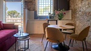 Una cucina accogliente con parete in pietra, una finestra, un forno a microonde e un'area pranzo con sedie e un tavolo.