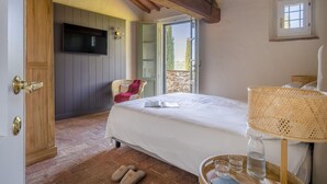 A bedroom with a bed, a television, a wicker side table, and a window. - Nice apartment in villa with WIFI, pool, patio and panoramic view, close to Greve In Chianti (Badia A Passignano)