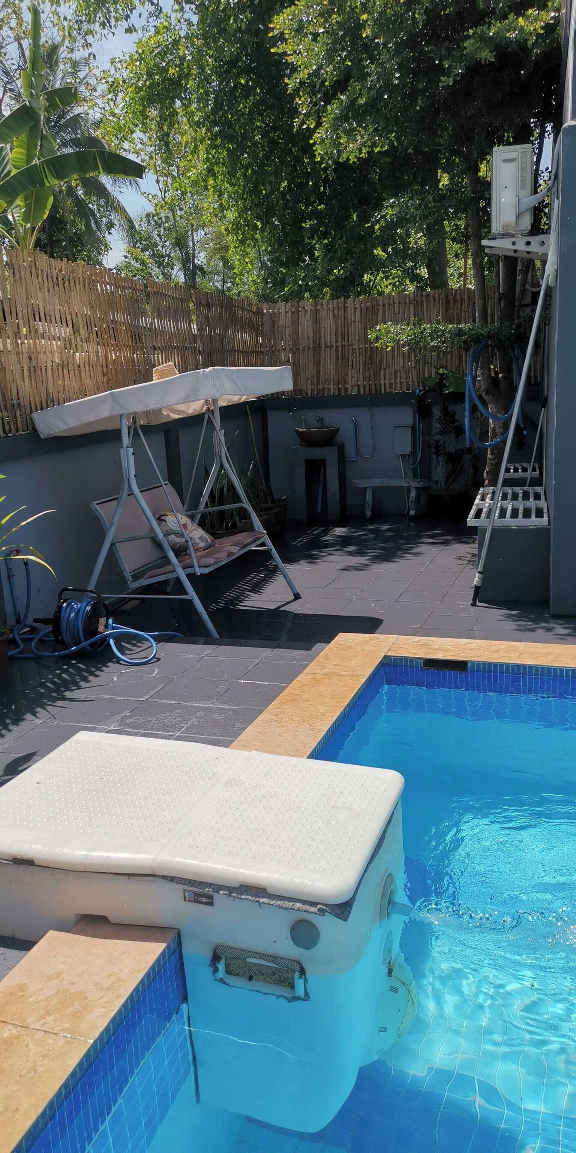 A swimming pool with a diving board and a covered seating area.