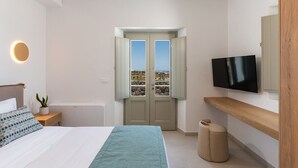 A bedroom with a bed, a TV, a window with a view, and a door.