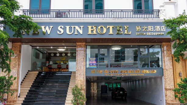 Exterior del Hotel New Sun, con una escalera que conduce a la entrada, un balcón arriba y un cartel con el nombre del hotel e información de contacto.