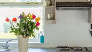 A kitchen with a window, a sink, a stove, and a vase with flowers. - Wonderful private villa for 4 guests with WIFI, TV and patio (Bodmin)