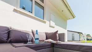 An outdoor seating area with a sofa, cushions, and a bottle of water.