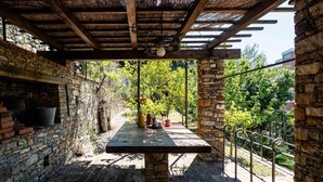 A covered outdoor seating area with a stone wall and a wooden table.