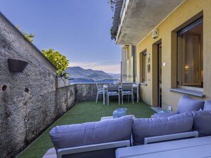 A terrace with a table and chairs, a sofa, and a view of the mountains.