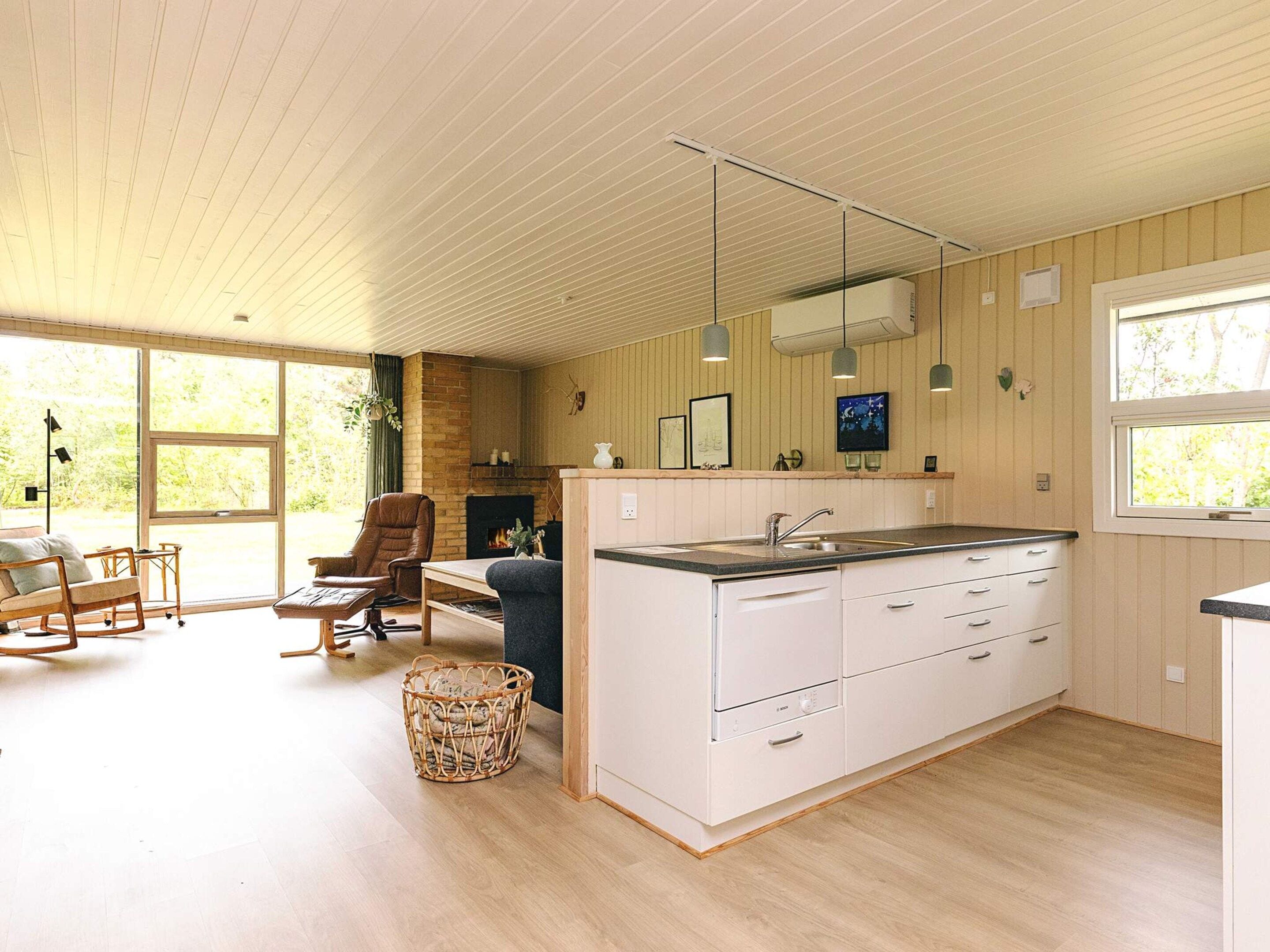A modern kitchen with a large island, wooden flooring, and a dining area with a fireplace.