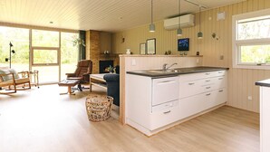 Una cocina moderna con una isla grande, piso de madera y un comedor con chimenea.
