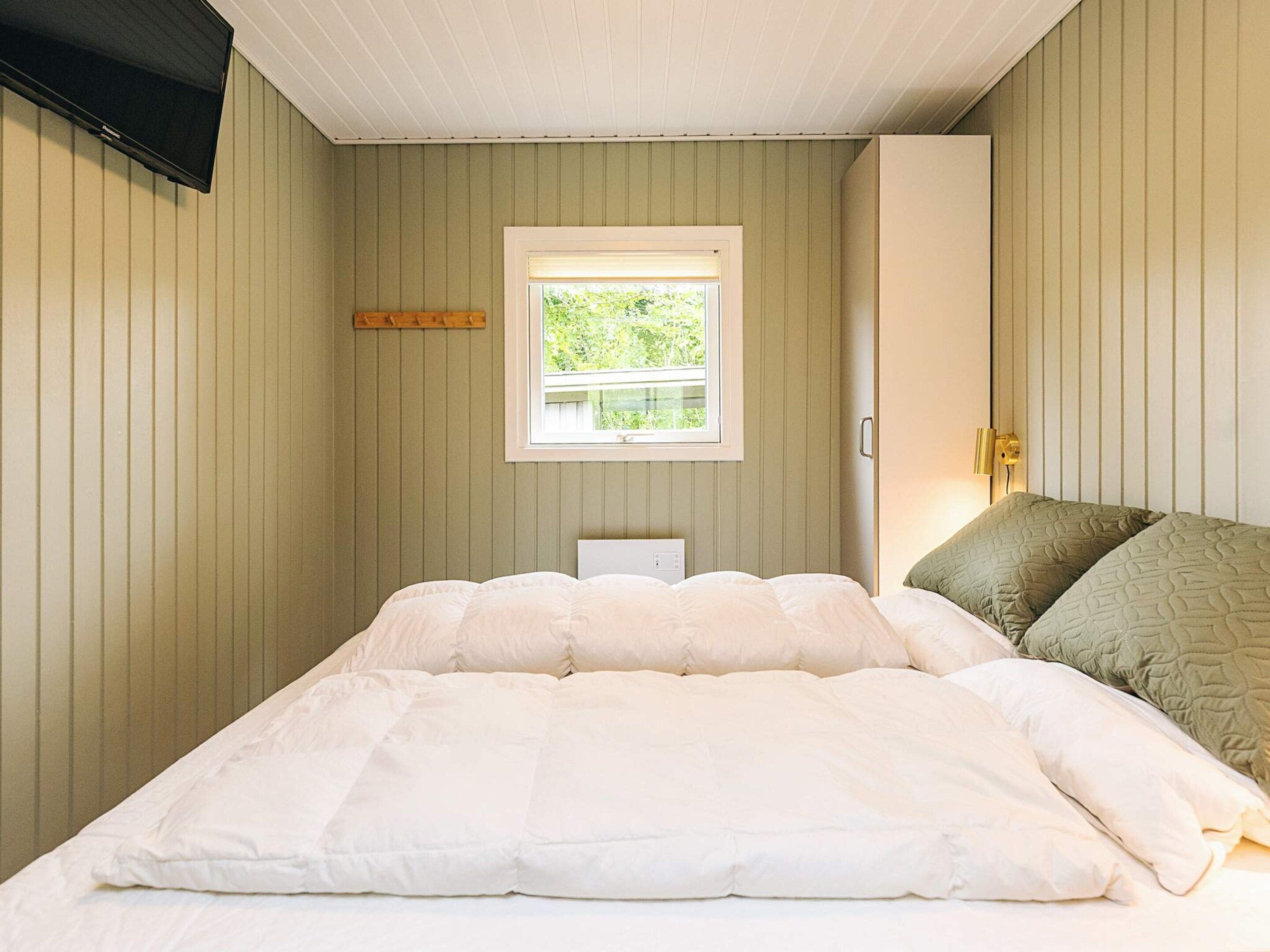 A bedroom with a bed, a window, and a bedside lamp.