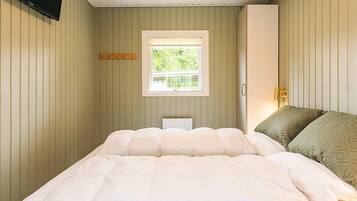 A bedroom with a bed, a window, and a bedside lamp.
