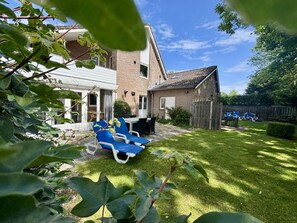 Un jardin avec un espace patio, une maison en briques et une clôture en bois.