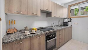 Une cuisine moderne avec des meubles en bois, un plan de travail en granit, un four encastré et une fenêtre donnant sur un paysage verdoyant.