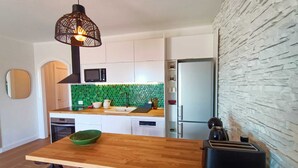 Eine moderne Küche mit einer Holzinsel, einem schwarzen Toaster, einer Mikrowelle und einem Kühlschrank.