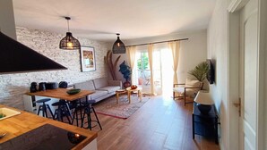 Ein modernes Wohnzimmer mit einem Holzesstisch, einer Couch und einem Couchtisch. Zwei Pendelleuchten hängen von der Decke.