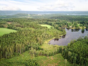 Un paysage boisé, avec une rivière, des champs ouverts et quelques bâtiments dispersés.