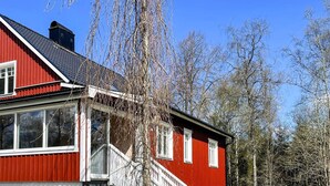 A red and white house with a porch and a table with chairs outside.