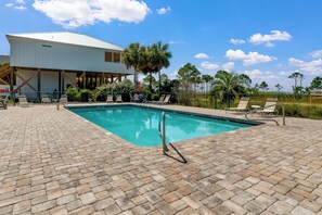 Ein Swimmingpool mit Liegestühlen, einer überdachten Terrasse und Blick auf die umliegende Landschaft.