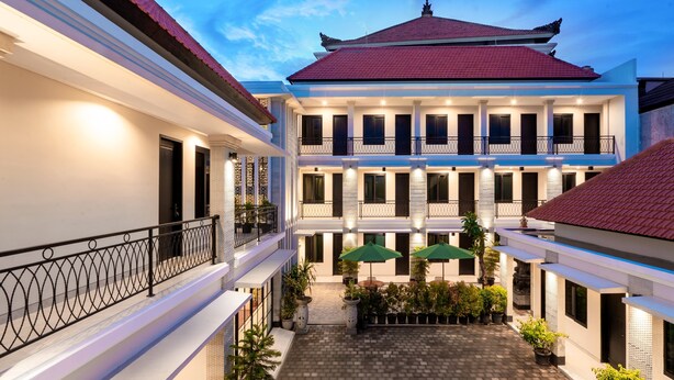 A multi-story building with a courtyard, featuring balconies, potted plants, and outdoor seating. - Bali Loop Coliving & Coworking (Mengwi)