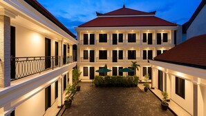 A multi-story building with a central courtyard, balconies, and potted plants. - Bali Loop Coliving & Coworking (Mengwi)