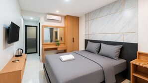A modern hotel room with a large bed, a desk with a mirror, a television, and an air conditioning unit. - Bali Loop Coliving & Coworking (Mengwi)