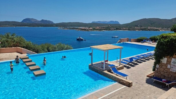 Une piscine à l’eau d’un bleu cristallin, une terrasse en bois et des chaises longues.