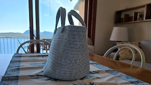 Une pièce avec une table dressée pour deux personnes, une nappe à motifs et une vue sur l’extérieur par une fenêtre.