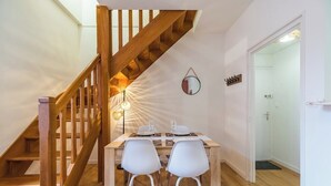 Ein Essbereich mit einer Holztreppe, einem für zwei Personen gedeckten Tisch und einem Spiegel an der Wand.