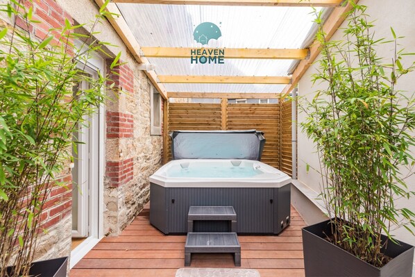 A hot tub in a covered outdoor area with wooden beams and bamboo plants. - Charming Duplex with Jacuzzi, Guingamp Center (Guingamp)