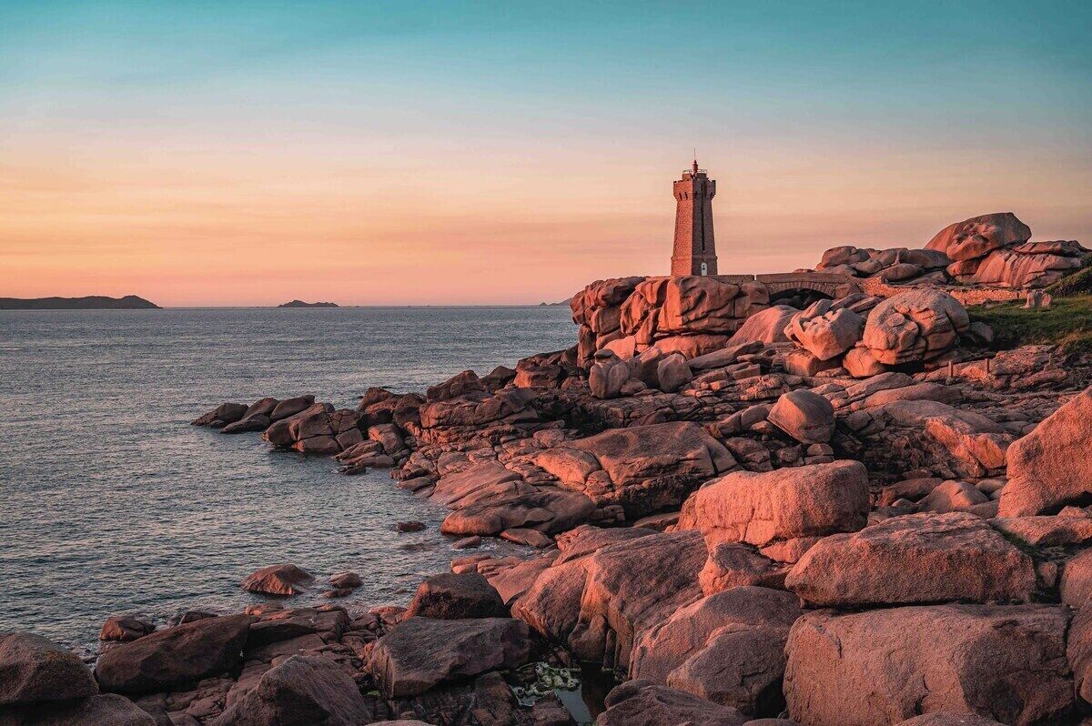 Un paysage côtier avec un phare situé sur un promontoire rocheux, dominant la mer.