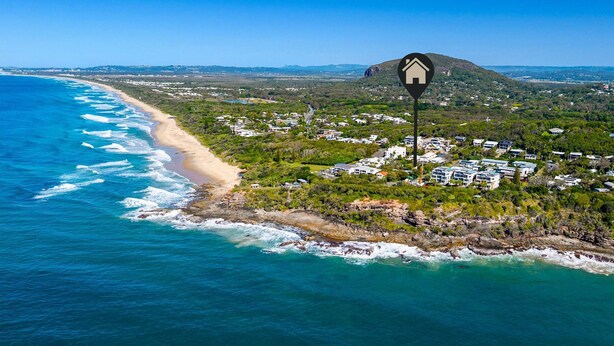 An aerial view of a coastal area with a beach, houses, and a mountain. - The Point Arkwright Bungalow (Point Arkwright)