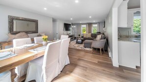 A spacious living area with a wooden dining table set for four, a sofa, and a coffee table.