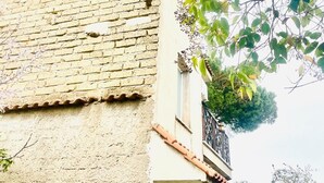 Un edificio con fachada de ladrillo, un balcón con barandilla metálica y una ventana.