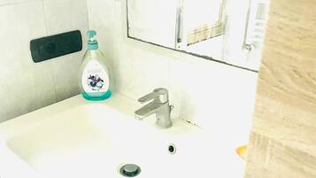 Une salle de bain avec un lavabo blanc, un miroir et un distributeur de savon.