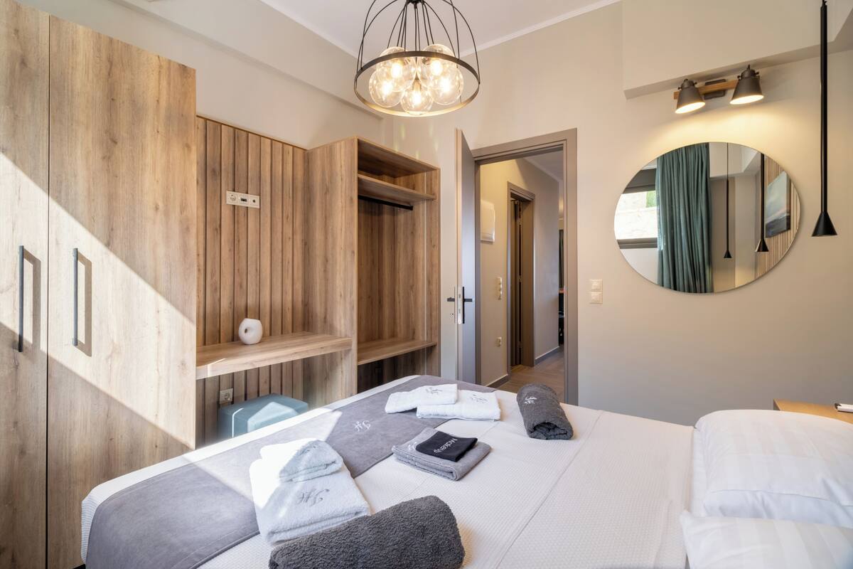 Une chambre d’hôtel moderne équipée d’un lit, d’une armoire en bois, d’un miroir et d’un luminaire au plafond.