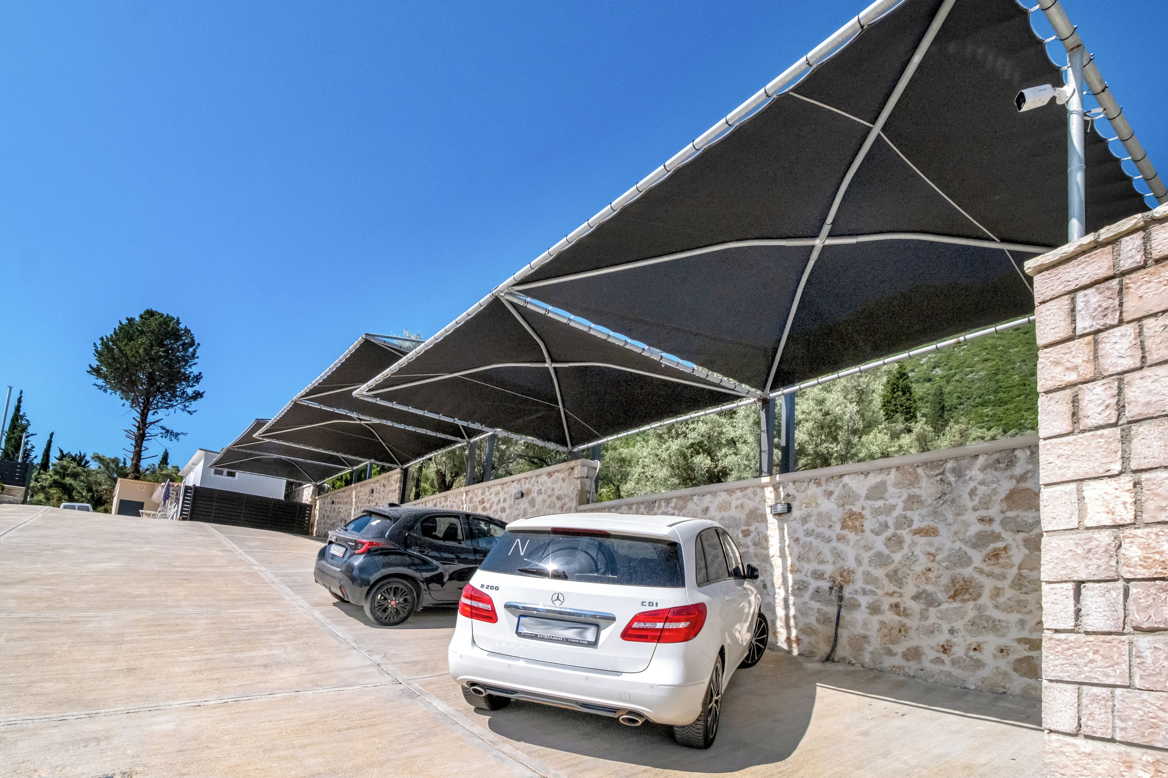 A covered parking area with a stone wall and a car parked inside.