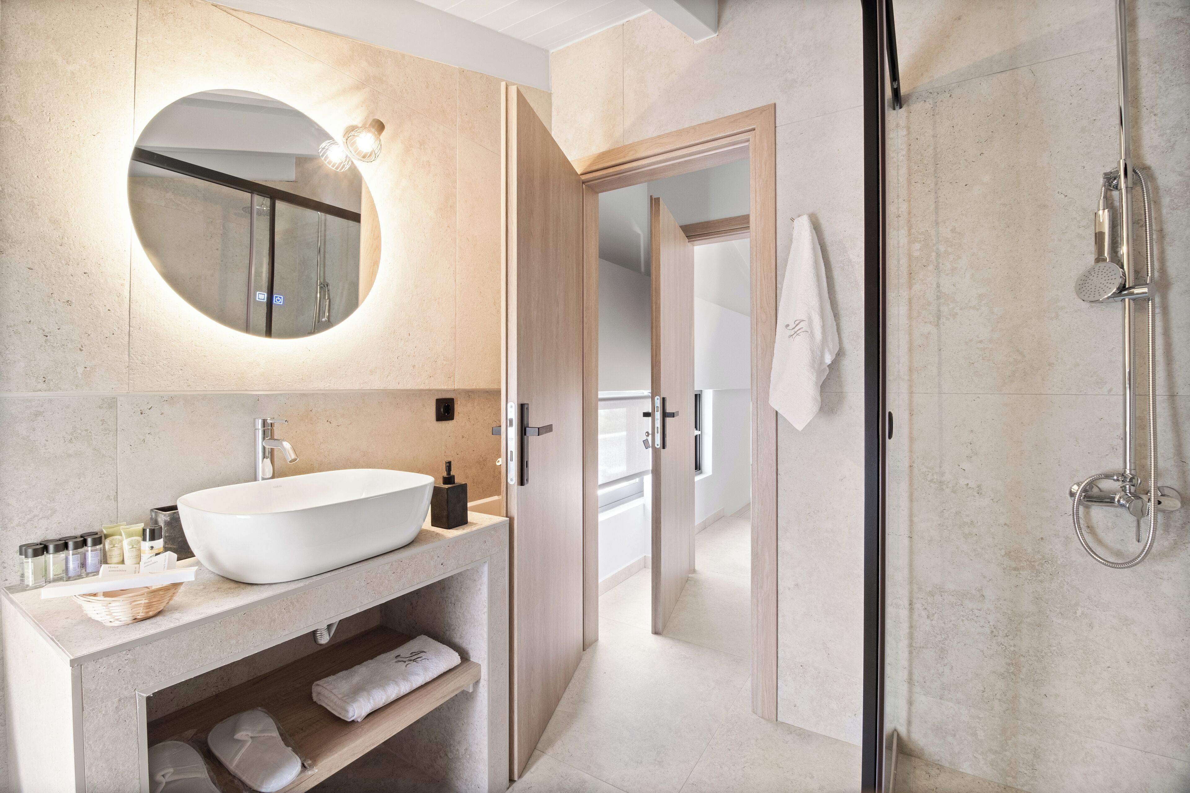 A modern bathroom with a large oval sink, a mirror, and a walk-in shower.