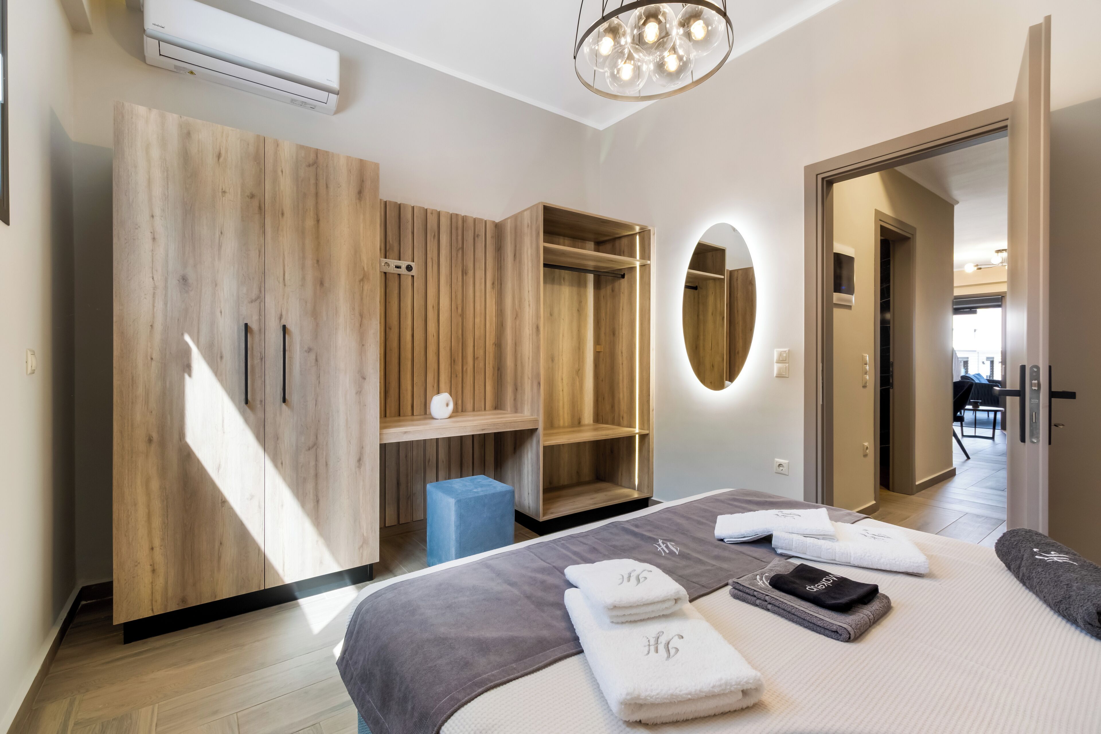 A modern bedroom with a large wardrobe, a bedside table, a mirror, and neatly folded towels.