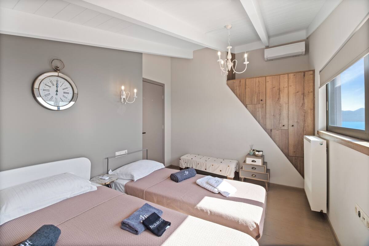Une chambre d’hôtel avec trois lits, un lustre, une horloge et une vue sur l’extérieur.