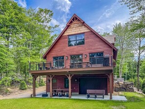 A two-story log cabin with a balcony, a garage, and a front porch.
