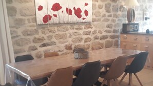 A dining area with a stone wall, a wooden table, and four chairs. - La ferme des Farios 4 pers (Tence)