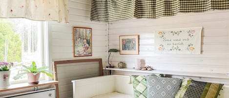 A bedroom with a bed, a dresser, a window with curtains, and wall decorations.