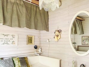 A room with a bed, a bedside table, a mirror, and a wall with a checkered curtain. - 5 Person Holiday Home in Hallstavik (Hallstavik)