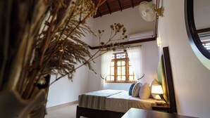 Une chambre à coucher avec un lit, une table de chevet, une lampe et une fenêtre avec des rideaux.