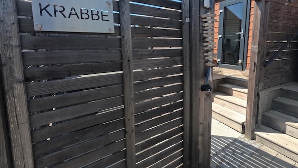 A wooden gate with a sign reading "KRABBE" and a modern building entrance with glass doors. - Crab on the Rhön beach with whirlpool (Wartmannsroth)